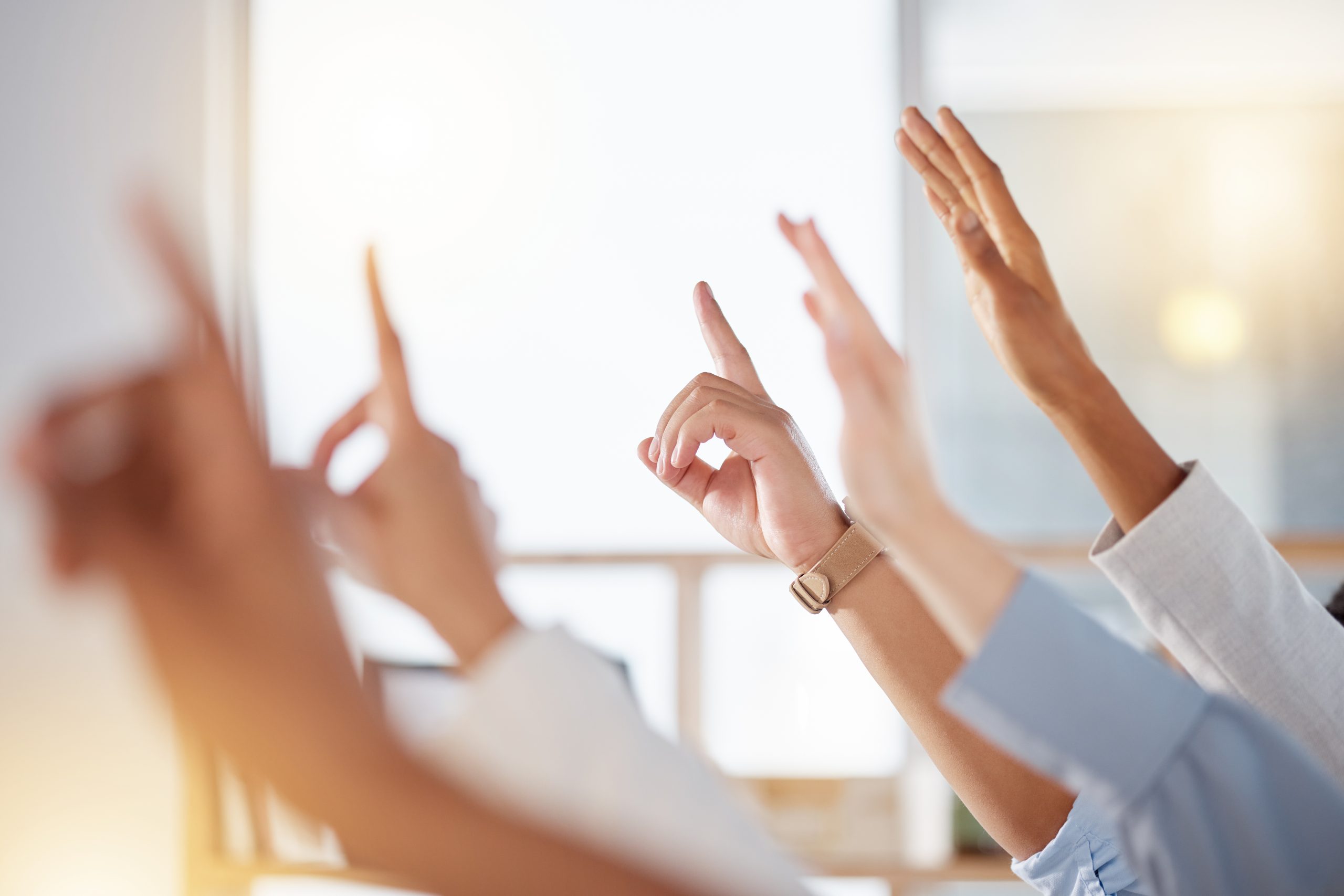 Seminar, diversity and business people raise hands to ask a question at training in the office. Group, multiracial and professional employees at a corporate tradeshow or conference in the workplace.